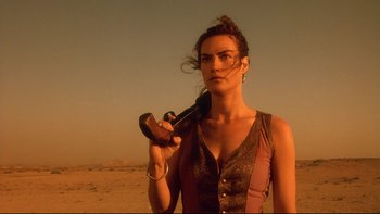 Movie still from “Dust Devil” (1992), directed by Richard Stanley – A woman holding a wrench in her hand in the desert; Close Up shot, Low angle