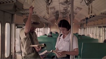 Movie still from “Dust in the Wind” (1986), directed by Hsiao-Hsien Hou – A man and a woman on a train looking at books; Medium shot, Low angle