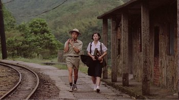 Movie still from “Dust in the Wind” (1986), directed by Hsiao-Hsien Hou – A man and a woman walking down a road; Wide shot, Low angle