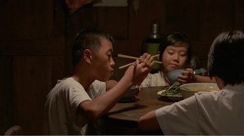 Movie still from “Dust in the Wind” (1986), directed by Hsiao-Hsien Hou – A group of people sitting at a table eating food with chopsticks; Medium shot, High angle