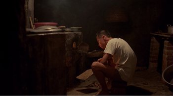 Movie still from “Dust in the Wind” (1986), directed by Hsiao-Hsien Hou – A man kneeling down in front of an oven; Wide shot, High angle