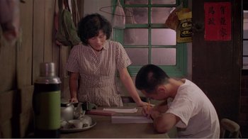 Movie still from “Dust in the Wind” (1986), directed by Hsiao-Hsien Hou – A man and a woman writing on a piece of paper at a table; Medium shot, High angle