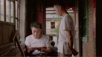 Movie still from “Dust in the Wind” (1986), directed by Hsiao-Hsien Hou – A man standing next to a woman in a room; Medium shot, Over the shoulder angle