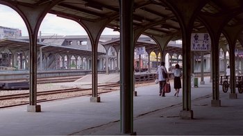 Movie still from “Dust in the Wind” (1986), directed by Hsiao-Hsien Hou – Two people are standing at a train station platform; Extreme Wide shot, High angle