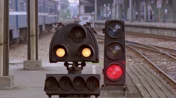 Movie still from “Dust in the Wind” (1986), directed by Hsiao-Hsien Hou – A traffic light sitting on the side of a road; Wide shot, Low angle