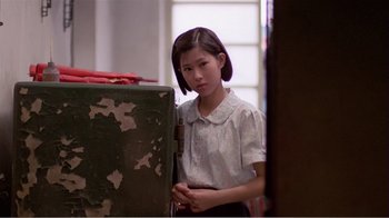 Movie still from “Dust in the Wind” (1986), directed by Hsiao-Hsien Hou – A young girl standing in front of an old suitcase; Medium shot, Over the shoulder angle