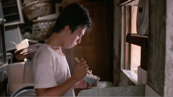 Movie still from “Dust in the Wind” (1986), directed by Hsiao-Hsien Hou – A man eating a bowl of food with chopsticks; Medium shot, Low angle