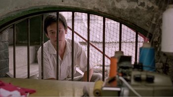 Movie still from “Dust in the Wind” (1986), directed by Hsiao-Hsien Hou – A man sitting in front of a cage; Medium shot, Low angle