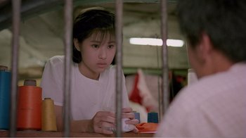 Movie still from “Dust in the Wind” (1986), directed by Hsiao-Hsien Hou – A young girl sitting at a table in front of a cell phone; Medium shot, High angle