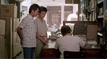Movie still from “Dust in the Wind” (1986), directed by Hsiao-Hsien Hou – Three men standing in front of a man sitting at a desk; Medium shot, Over the shoulder angle
