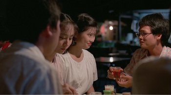 Movie still from “Dust in the Wind” (1986), directed by Hsiao-Hsien Hou – A group of people sitting at a table with drinks; Medium shot, Over the shoulder angle