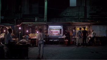 Movie still from “Dust in the Wind” (1986), directed by Hsiao-Hsien Hou – People are standing in an open market at night; Extreme Wide shot, High angle