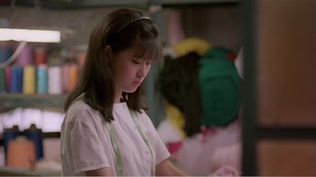 Movie still from “Dust in the Wind” (1986), directed by Hsiao-Hsien Hou – A woman in a white shirt is sewing a dress; Medium shot, Over the shoulder angle
