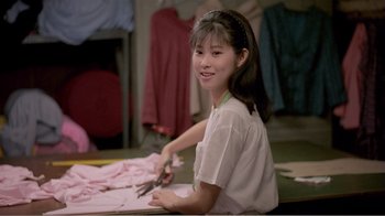 Movie still from “Dust in the Wind” (1986), directed by Hsiao-Hsien Hou – A young girl sitting at a table cutting paper with a pair of shears; Medium shot, Over the shoulder angle