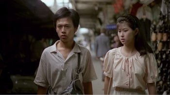 Movie still from “Dust in the Wind” (1986), directed by Hsiao-Hsien Hou – A man and a woman walking down a street; Medium shot, Low angle