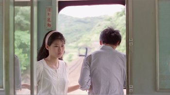 Movie still from “Dust in the Wind” (1986), directed by Hsiao-Hsien Hou – A woman standing next to a man on a train; Medium shot, Over the shoulder angle