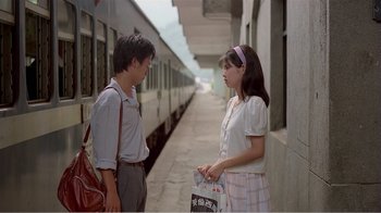 Movie still from “Dust in the Wind” (1986), directed by Hsiao-Hsien Hou – A man and a woman standing next to each other on the side of a train platform; Medium shot, Over the shoulder angle