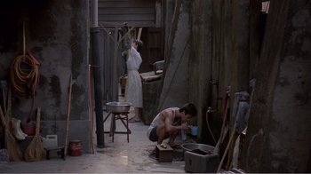 Movie still from “Dust in the Wind” (1986), directed by Hsiao-Hsien Hou – A man and a woman are painting in an alley; Wide shot, High angle