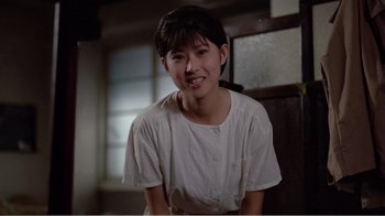 Movie still from “Dust in the Wind” (1986), directed by Hsiao-Hsien Hou – A young asian woman smiling for the camera; Medium shot, Low angle