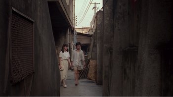 Movie still from “Dust in the Wind” (1986), directed by Hsiao-Hsien Hou – Two people walking down a street in a city; Wide shot, High angle