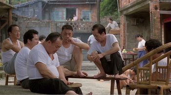 Movie still from “Dust in the Wind” (1986), directed by Hsiao-Hsien Hou – A group of men sitting on top of a wooden bench; Wide shot, High angle