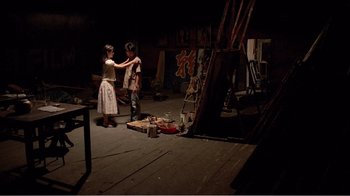 Movie still from “Dust in the Wind” (1986), directed by Hsiao-Hsien Hou – A couple of people standing in front of a painting; Wide shot, High angle