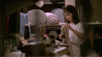 Movie still from “Dust in the Wind” (1986), directed by Hsiao-Hsien Hou – A young woman is working in a sewing room; Medium shot, Over the shoulder angle