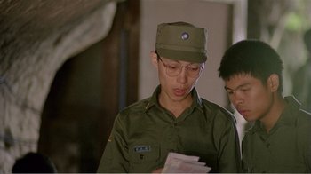 Movie still from “Dust in the Wind” (1986), directed by Hsiao-Hsien Hou – A man wearing a hat and glasses looking down at a piece of paper; Close Up shot, Over the shoulder angle