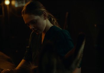 Movie still from “EO” (2022), directed by Jerzy Skolimowski – A woman in a dark room looking down at a piece of paper; Medium shot, Over the shoulder angle