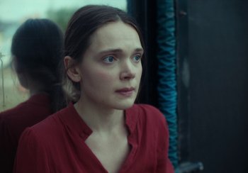 Movie still from “EO” (2022), directed by Jerzy Skolimowski – A woman in a red shirt is sitting on a bus; Close Up shot, Over the shoulder angle
