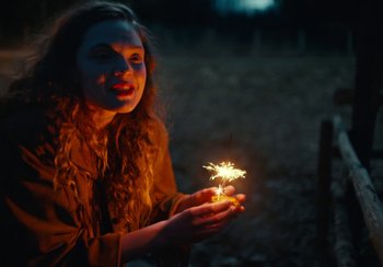 Movie still from “EO” (2022), directed by Jerzy Skolimowski – A woman holding a sparkler in her hand; Close Up shot, Low angle