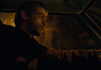 Movie still from “EO” (2022), directed by Jerzy Skolimowski – A man sitting in a car looking out the window at night; Close Up shot, Low angle