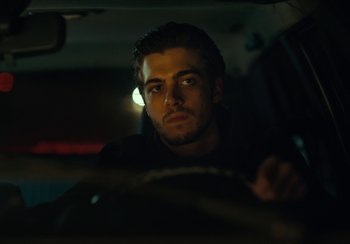 Movie still from “EO” (2022), directed by Jerzy Skolimowski – A man sitting in the driver's seat of a car at night; Close Up shot, Low angle