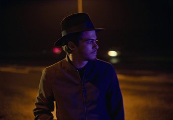 Movie still from “EO” (2022), directed by Jerzy Skolimowski – A man wearing a hat standing in the dark at night; Close Up shot, Low angle