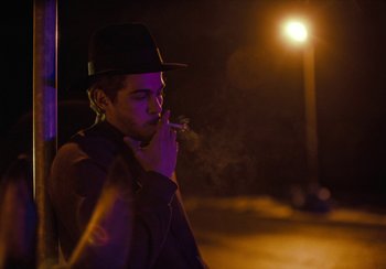 Movie still from “EO” (2022), directed by Jerzy Skolimowski – A young man wearing a fedora smoking a cigarette; Medium shot, Low angle
