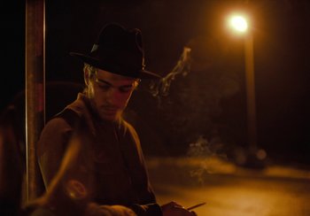 Movie still from “EO” (2022), directed by Jerzy Skolimowski – A man in a hat is smoking a cigarette; Close Up shot, Low angle