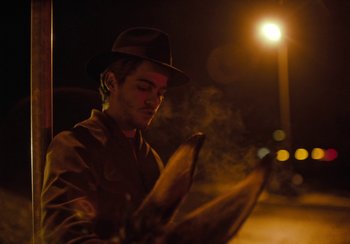 Movie still from “EO” (2022), directed by Jerzy Skolimowski – A man wearing a hat is smoking a cigarette; Close Up shot, Low angle