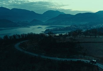 Movie still from “EO” (2022), directed by Jerzy Skolimowski – A view of a lake from a hill at dusk; Extreme Wide shot, High angle
