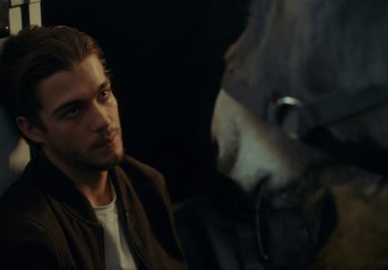 Movie still from “EO” (2022), directed by Jerzy Skolimowski – A man sitting in front of another man in a dark room; Close Up shot, Over the shoulder angle