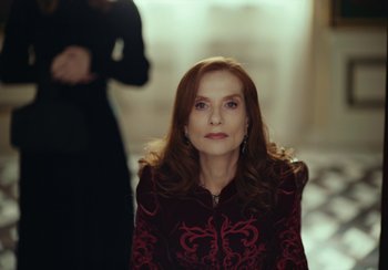 Movie still from “EO” (2022), directed by Jerzy Skolimowski – A woman with long red hair wearing a red and black dress; Medium shot, Over the shoulder angle