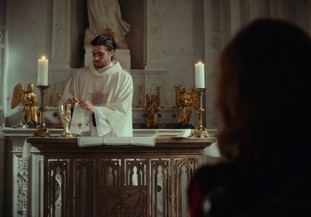 Movie still from “EO” (2022), directed by Jerzy Skolimowski – A priest is standing at the altar of a catholic church; Medium shot, Low angle