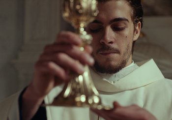 Movie still from “EO” (2022), directed by Jerzy Skolimowski – A man holding a gold goblet in front of his face; Close Up shot, Low angle