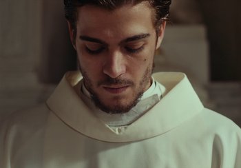 Movie still from “EO” (2022), directed by Jerzy Skolimowski – A person wearing a priest's outfit; Close Up shot, Low angle