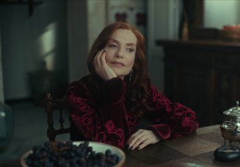 Movie still from “EO” (2022), directed by Jerzy Skolimowski – A woman sitting in front of a bowl of grapes; Medium shot, Over the shoulder angle