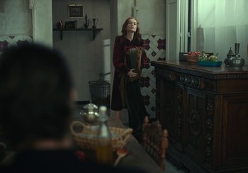 Movie still from “EO” (2022), directed by Jerzy Skolimowski – A woman standing in a kitchen holding a book; Medium shot, Over the shoulder angle