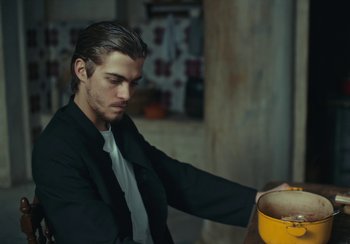 Movie still from “EO” (2022), directed by Jerzy Skolimowski – A man sitting in front of a yellow bowl; Medium shot, Low angle