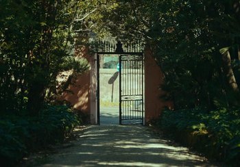 Movie still from “EO” (2022), directed by Jerzy Skolimowski – An open gate leading to a path in a garden; Extreme Wide shot, High angle