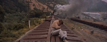 Movie still from “East of Eden” (1955), directed by Elia Kazan – A man sitting on the side of a train tracks; Wide shot, High angle