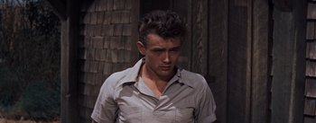 Movie still from “East of Eden” (1955), directed by Elia Kazan – A young man in a white shirt is standing in front of a wooden wall; Close Up shot, Low angle