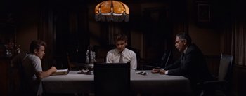 Movie still from “East of Eden” (1955), directed by Elia Kazan – A man sitting at a table in front of two other men; Medium shot, High angle